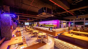A restaurant with wooden tables and chairs, a bar area, and a stone wall. - The Monarch (Navi Mumbai)