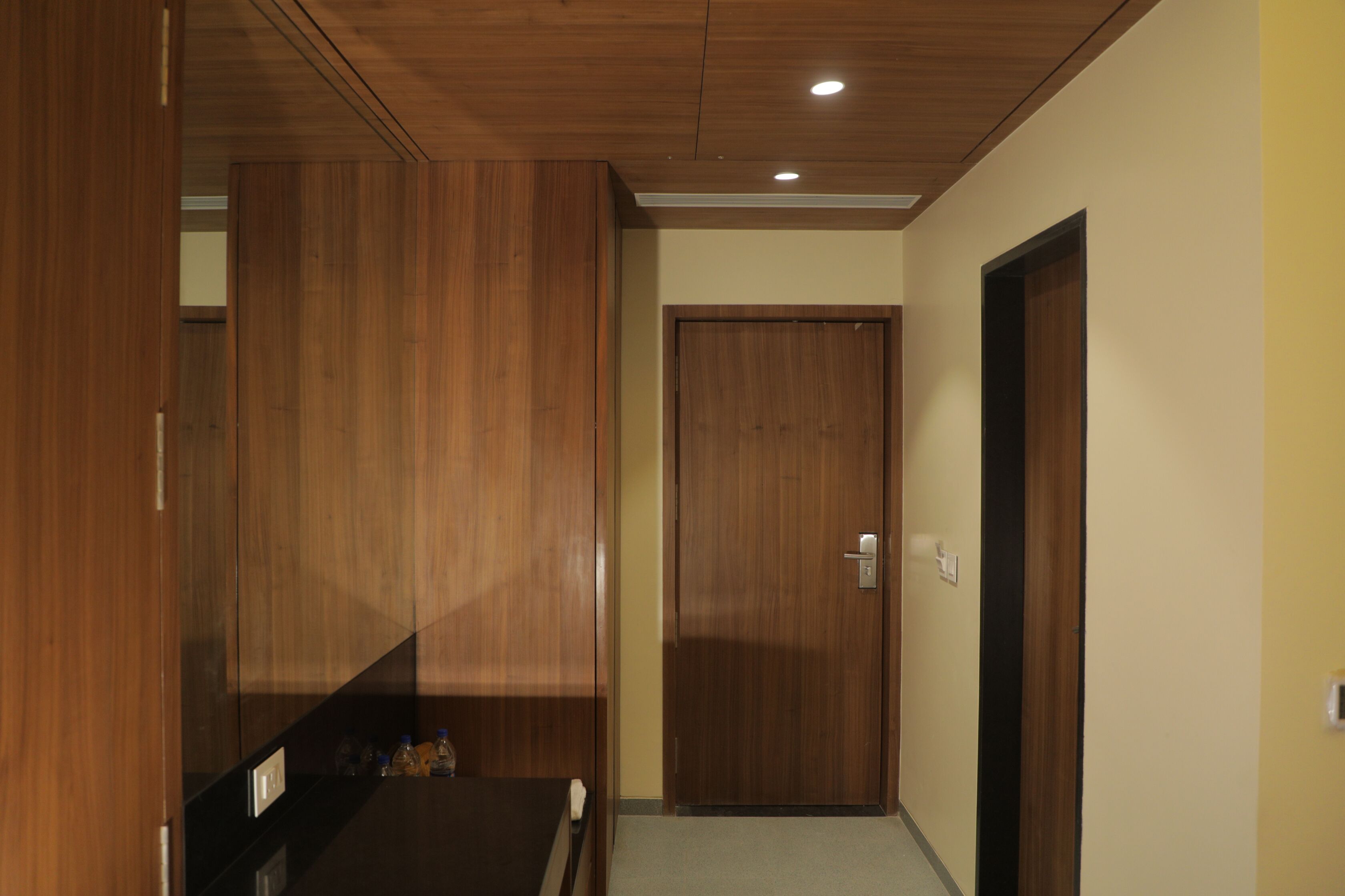 A hallway with wooden paneling, a door, and a small table with bottles.
