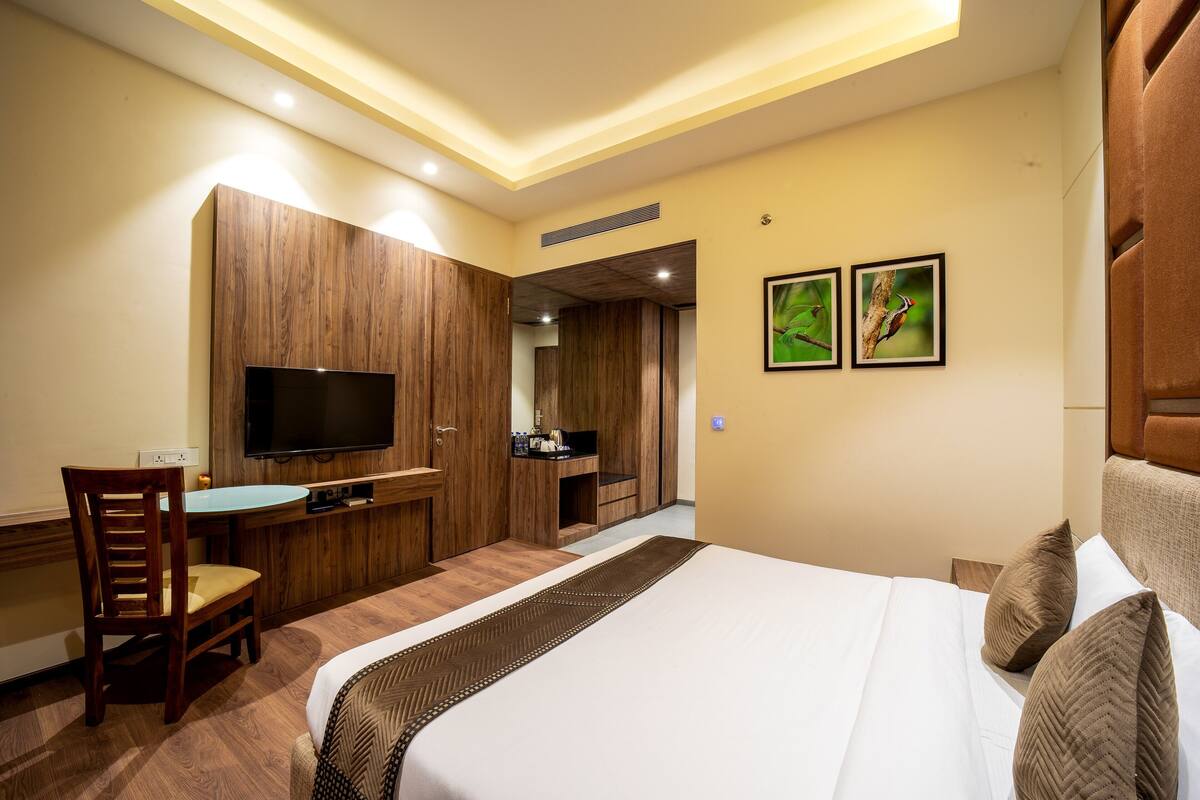 A hotel room with a bed, a desk, a television, and a mirror.