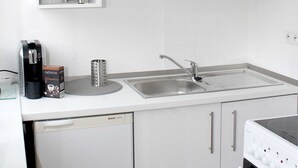 Eine moderne Küche mit weißen Schränken, einem Bosch Geschirrspüler, einer Spüle und einem Herd.
