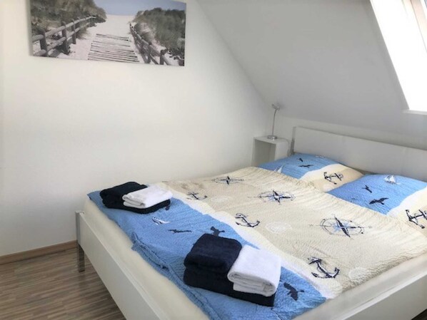 A bedroom with a bed, a nightstand, a wall-mounted picture, and a sloped ceiling.