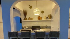 An outdoor kitchen with a grill, bar stools, and decorative items.