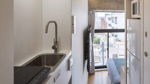 Una cocina moderna y estrecha con horno empotrado, lavamanos y una pequeña zona de comedor con banco.