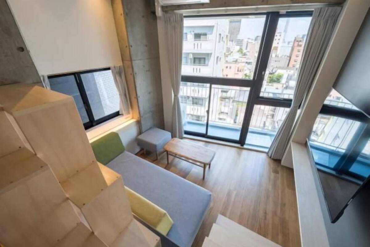 A modern apartment with a view of the city, a wooden staircase, and a small seating area.