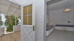 Ein Zimmer mit weißer Tür, einer Bank, einem kleinen Tisch und Blick auf das Meer.