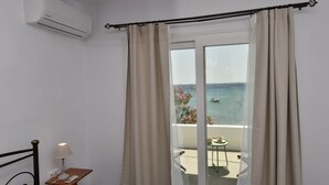 Ein Zimmer mit einem Bett, einem Nachttisch mit Lampe und Meerblick durch eine Balkontür.