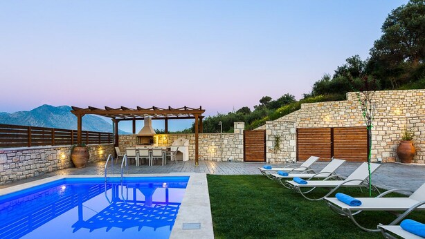 A pool area with lounge chairs, a pergola, and a stone wall. - Renta Villa Georgios, with Pool, BBQ & Playground, Close to the beach (Perama)