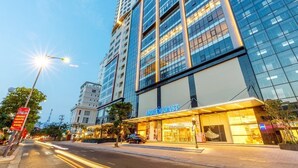 Ein modernes Hotel mit einem gut sichtbaren 'Gold Coast'-Schild, hoch aufragenden Gebäuden im Hintergrund und einer gut beleuchteten Straße.