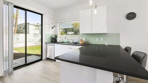 Een moderne keuken met een groot eiland, witte kastjes en een groene spatwand.