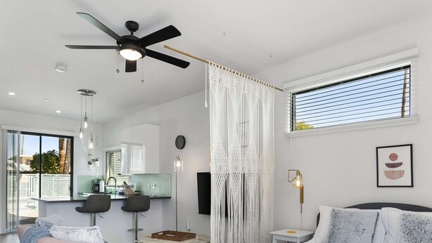 Een moderne slaapkamer met een groot bed, een plafondventilator, een zithoek en uitzicht op de omgeving.