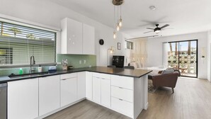 Een moderne keuken met witte kasten, een groot eiland en een zithoek met een bank en stoelen.