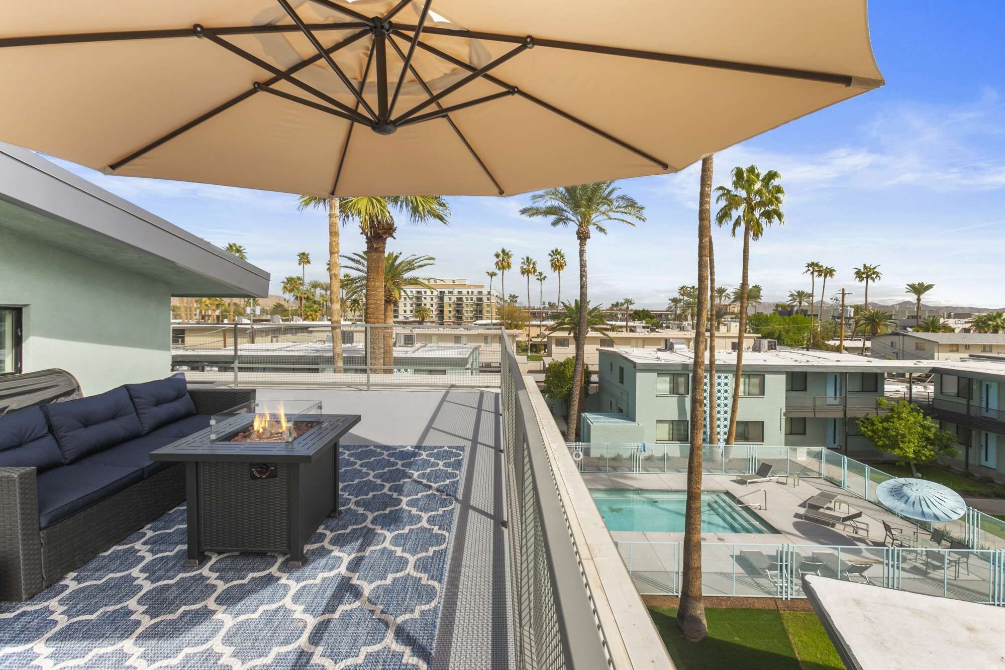A rooftop terrace with a sofa, a fire pit, and a pool area.