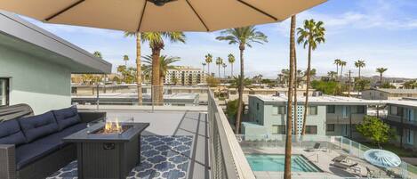 A rooftop terrace with a sofa, a fire pit, and a pool area.