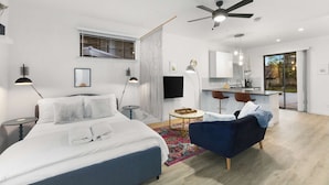 A modern bedroom with a bed, a blue armchair, a desk, and a ceiling fan. - Poolside studio with rooftop deck (Scottsdale)
