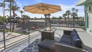 Une terrasse extérieure avec un espace salon, un foyer et un grand parasol.