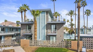 A modern building with multiple balconies, palm trees, and a clear sky.