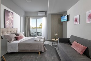 A modern hotel room with a bed, a sofa, a TV, and a balcony. - Golden Sunlight (Hersonissos)