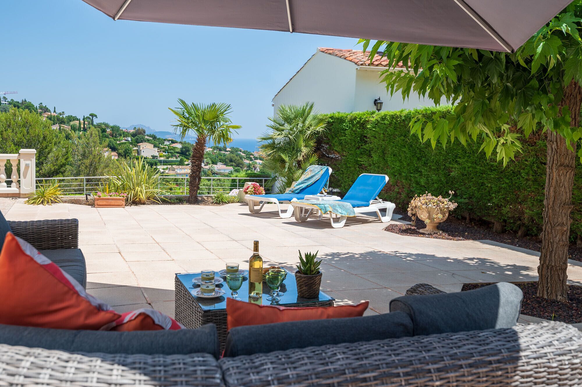 An outdoor patio with lounge chairs, a table with drinks, and a view of the sea.