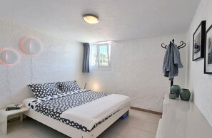 Un dormitorio con una cama, una mesita de noche, una ventana y un perchero en la pared con toallas.