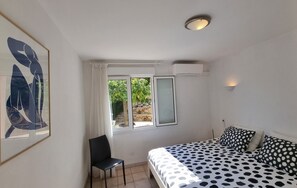 Ein Schlafzimmer mit Bett, Stuhl, Fenster und Deckenleuchte.