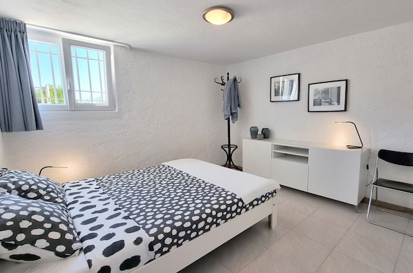 Ein Schlafzimmer mit einem Bett, einem Schreibtisch, einem Stuhl und einem Fenster.