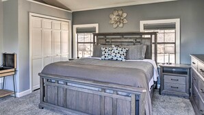 A bedroom with a large bed, a nightstand, a dresser, and a wardrobe. - Pet-Friendly Branson Area Home: Hot Tub, Game Room (Reeds Spring)