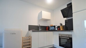 Una cocina moderna con armarios blancos, horno empotrado, microondas y refrigerador.