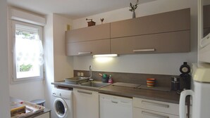 A compact kitchen with a washing machine, dishwasher, and a small countertop with various items.