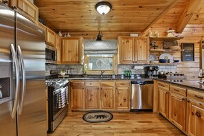 A kitchen with wooden cabinets, stainless steel appliances, and a wooden floor. - Above & Beyond Lodge | Blue Ridge, Ga (Blue Ridge)