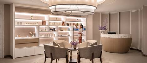 A modern reception area with a central chandelier, a reception desk, and a seating area with chairs and a table.
