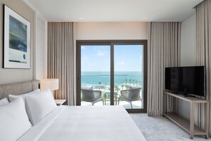 A hotel room with a large bed, a TV on a stand, a balcony with a view of the sea, and a framed picture on the wall. - Address Beach Resort Fujairah (Al Aqah)