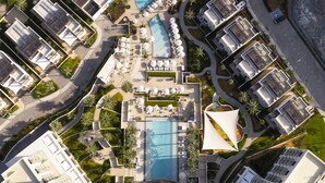 An aerial view of a resort with multiple swimming pools, sun loungers, and palm trees. - Address Beach Resort Fujairah (Al Aqah)