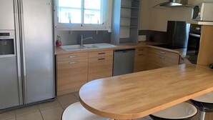 Uma cozinha moderna com frigorífico em aço inoxidável, forno embutido, pia e armários de madeira.