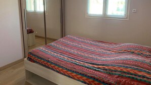 Quarto com cama, guarda-roupa e janela.