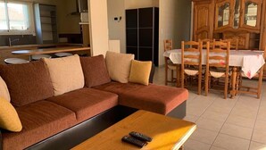 Uma sala de estar com um sofá marrom, uma mesa de centro de madeira e uma mesa de jantar com cadeiras.