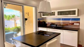 A modern kitchen with a black countertop, white cabinets, and a large window. - 3-bedroom Villa in Mèze with Garden and Air Conditioning (Mèze)
