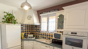 A compact kitchen with white cabinets, a tiled backsplash, a refrigerator, a microwave, an oven, and a sink. - Air-conditioned house in Mèze with garden and private parking (Mèze)