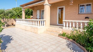 A two-story house with a covered patio, a door with a glass panel, and a small garden area with plants and flowers. - Air-conditioned house in Mèze with garden and private parking (Mèze)