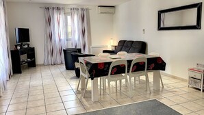 A living room with a dining table, chairs, a TV, and a sofa. - Air-conditioned house in Mèze with garden and private parking (Mèze)