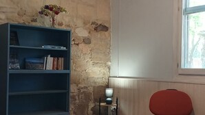 Una stanza con una libreria, un tavolo, una lampada e una finestra.