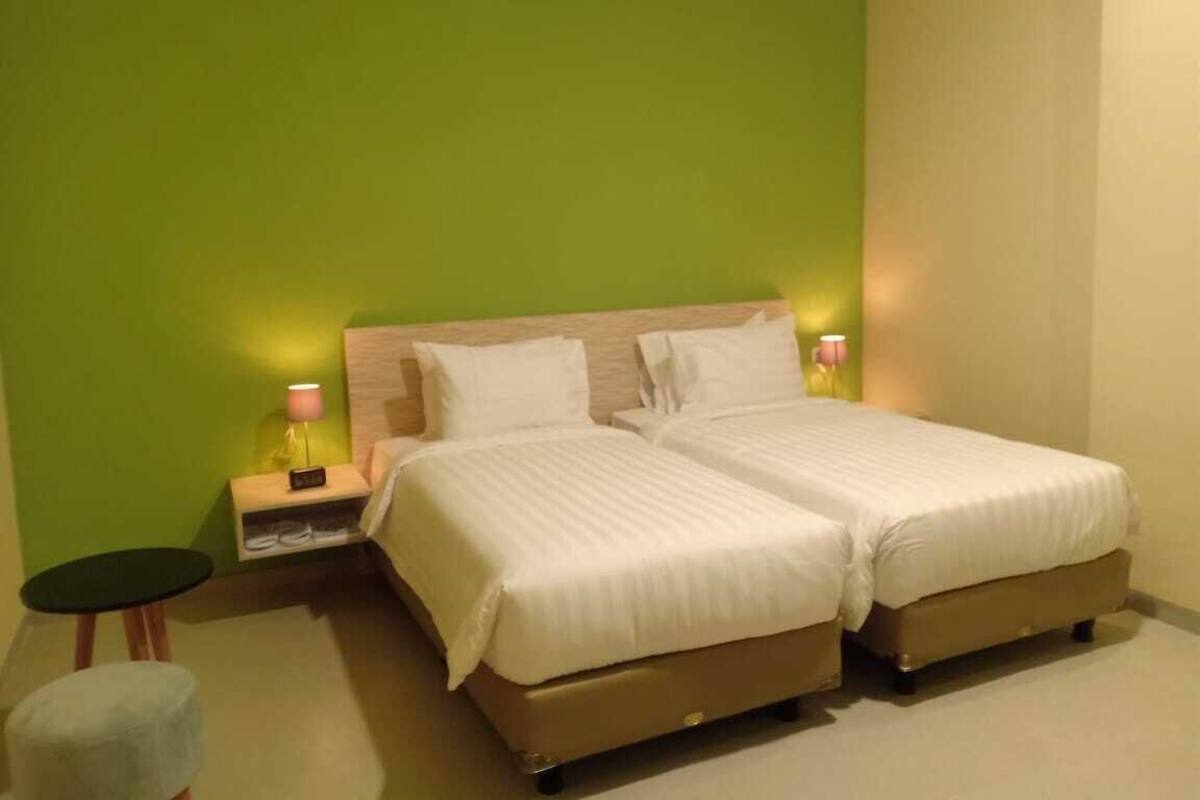 Une chambre d’hôtel avec deux lits, une table de chevet, une lampe et une petite table.