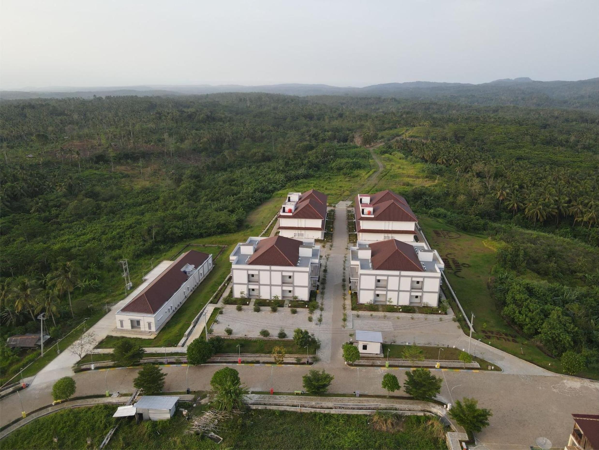 A modern hotel complex with multiple buildings, a central courtyard, and surrounding lush greenery.