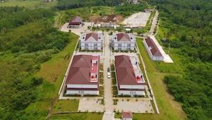 An aerial view of a residential area with multiple buildings, a clear view of the sea, and a distant island. - Asoka Resort Banten (Panimbang)