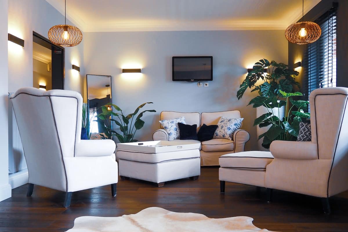 Una sala de estar moderna con un sofá, dos sillones, una mesa de centro y una planta grande en maceta.