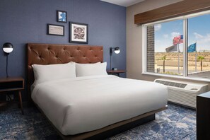 A hotel room with a large bed, a window with an American flag, and a view of a desert landscape. - Four Points by Sheraton Yuma (Yuma)