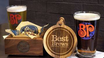 Un posavasos de madera con la marca 'Best Brews', una caja de madera con la marca 'Best Brews' y 'Four Points by Sheraton', y dos vasos de cerveza con la marca 'Best Brews'.