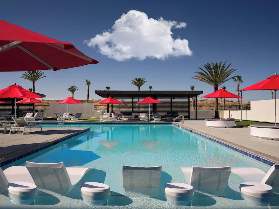 A pool area with sun loungers and red umbrellas.