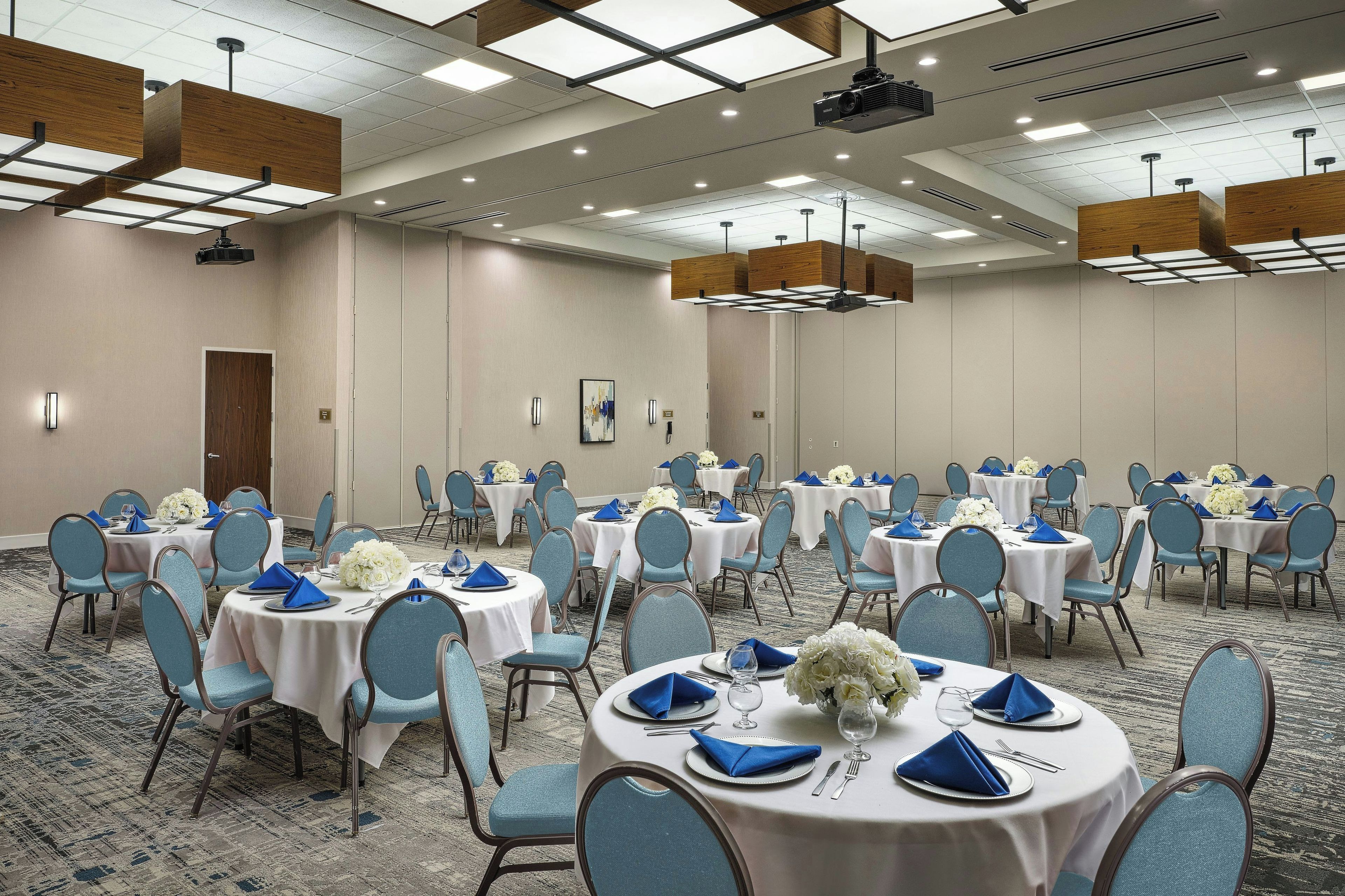 A conference room with multiple tables, chairs, and a projector.