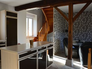 Una habitación con escalera de madera, zona de comedor y cocina.