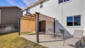 A covered patio with outdoor furniture, a pergola, and a wooden fence.